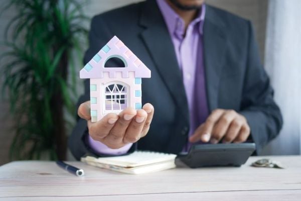 Businessman in suit holding a model house 600 Pexels